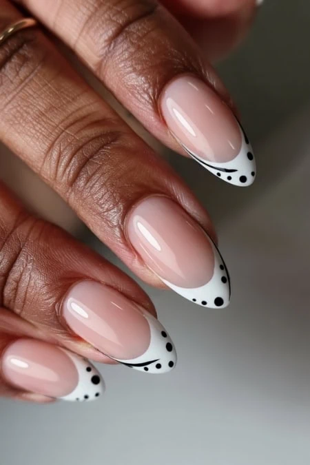 Elegant French manicure with black dotted accents on almond-shaped nails, perfect for sophisticated and trendy nail art styles.