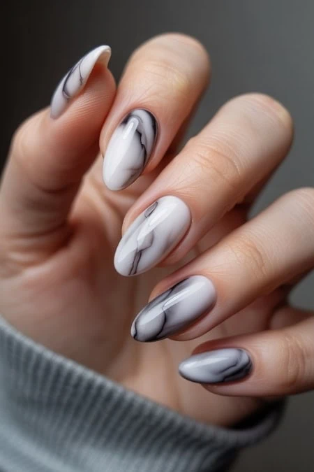 Marble gel manicure with black, white, and gray swirls on almond-shaped nails for a chic, modern nail art look. Perfect for stylish women seeking trendy, sophisticated nail designs.