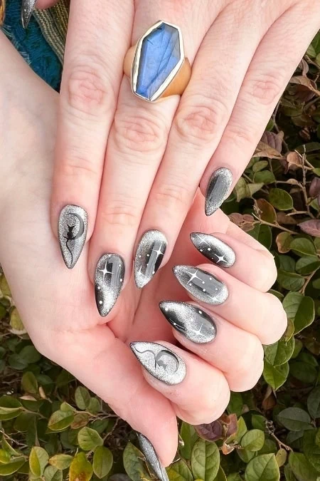 Silver galaxy-themed nail art with star and moon designs, featuring cosmic-inspired manicure for a celestial look.