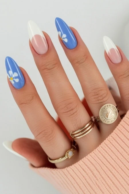 Colorful floral nail art with blue and white designs on manicured nails, showcasing trendy spring nail polish trends.