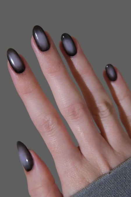 Elegant metallic black ombre nail manicure on feminine hand with smooth skin and neatly shaped nails, showcasing trendy nail art perfect for beauty and style enhancement.