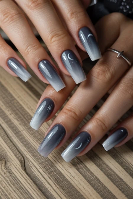 Dark blue to light gray ombre moon and star nail art design on manicured fingernails, perfect for nighttime elegance and celestial-themed nail art.