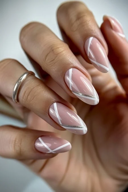 Elegant nude and white French manicure with silver accents on well-manicured nails, close-up shot showcasing detailed nail art and glossy finish, perfect for beauty, fashion, and nail design enthusiasts.
