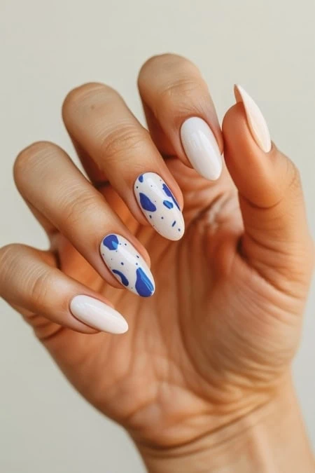 Elegant white and blue splatter nail art featuring a clean, modern design with glossy finish perfect for trendy manicures and beauty enthusiasts.