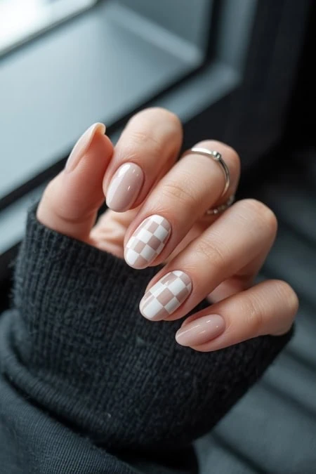Elegant neutral-toned manicure with checkered accent nails, perfect for beauty and self-care enthusiasts looking for stylish nail art ideas.
