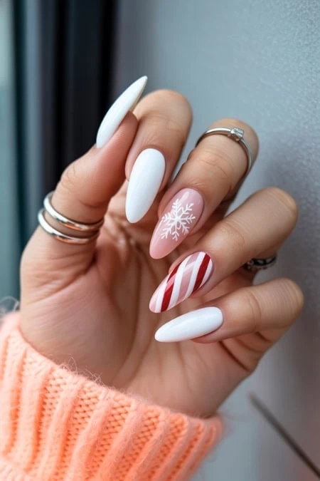 Stylish winter nail art with white and red striped, snowflake, and glossy finishes on manicured nails.