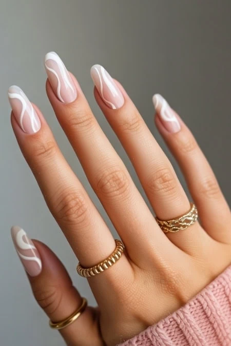 Elegant white French manicure with wavy design on natural nails, accessorized with gold rings, perfect for beauty and nail art inspiration.