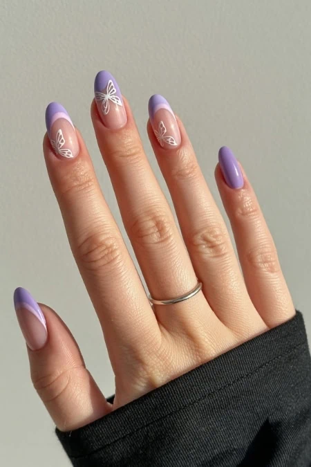 Elegant butterfly nail art with pastel purple and peach tones on almond-shaped nails, featuring detailed butterfly designs for a trendy and delicate look.