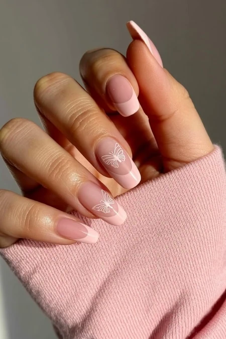 Delicate manicure with butterfly nail art on natural pink nails, featuring a soft pink nail polish and elegant white butterfly designs, perfect for beauty and self-care.