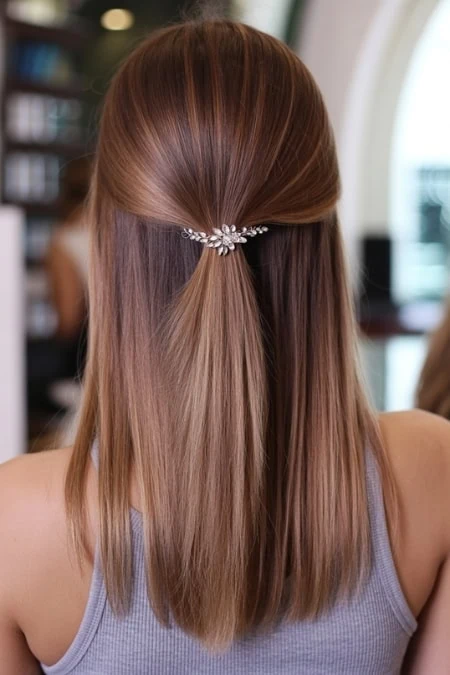 Soft caramel and blonde layered hair with a decorative hair clip, styled in a half-up, half-down look for a natural beauty and hair care theme.