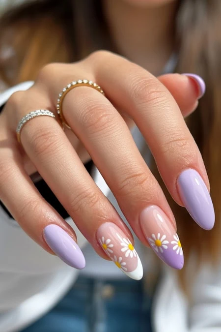 Colorful nail art with daisy designs, manicured nails, and elegant rings, showcasing trendy nude and lavender shades, perfect for spring and summer beauty trends.