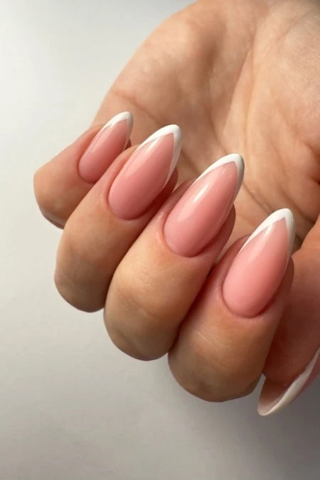 Elegant nude and white French manicure on well-groomed nails, showcasing perfect nail design and healthy cuticles for a polished look.