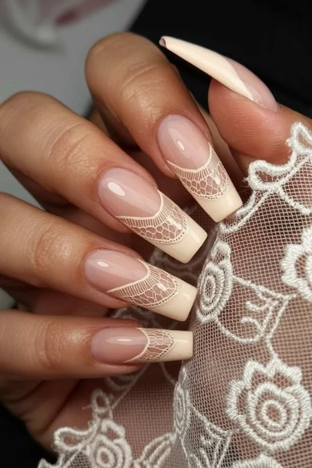 Elegant nude and white lace design acrylic nails showcasing intricate nail art and perfect manicure with long coffin-shaped tips.