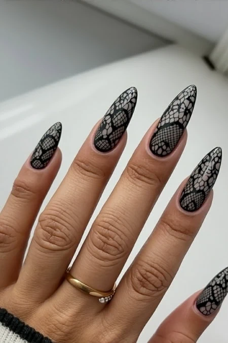 Intricate black lace nail design on long almond-shaped nails, perfect for elegant and stylish nail art enthusiasts, showcasing detailed henna-inspired patterns.
