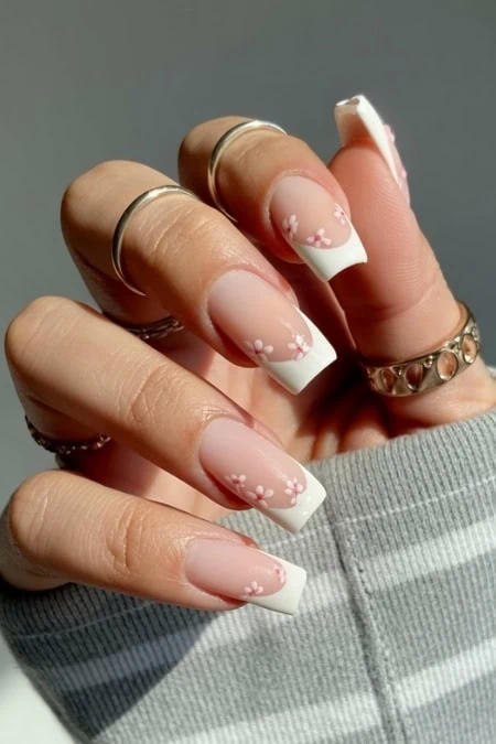 Elegant floral French manicure with white tips and daisy designs, perfect for a sophisticated and stylish nail art look. Ideal for beauty and nail art enthusiasts seeking trendy, chic manicure inspiration.