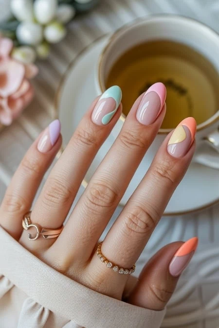 Colorful pastel nail art with gel polish design on manicured fingernails, beauty and skincare concept, neatly shaped nails, elegant rings, and a hot cup of tea on a cozy surface.