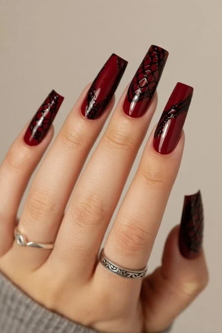 Glamorous red matte and glossy manicure with black snake skin design on long coffin-shaped acrylic nails, perfect for trendy nail art and beauty styling.