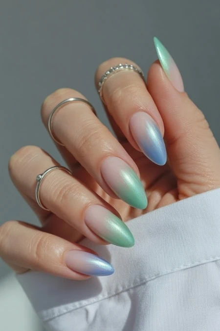 Colorful ombre nails with pearlescent finish and rings, perfect for nail art and beauty enthusiasts.