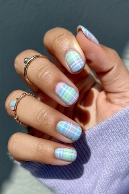 Pastel plaid nail art design with light blue, green, and white colors, perfect for spring and summer fashion. Well-manicured nails complemented by delicate rings showcase trendy and cute nail art.