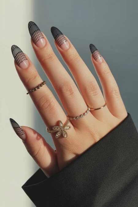 Elegant hand with black geometric nail art, adorned with delicate rings, showcasing trendy accessories and sophisticated nail design for beauty and fashion enthusiasts.