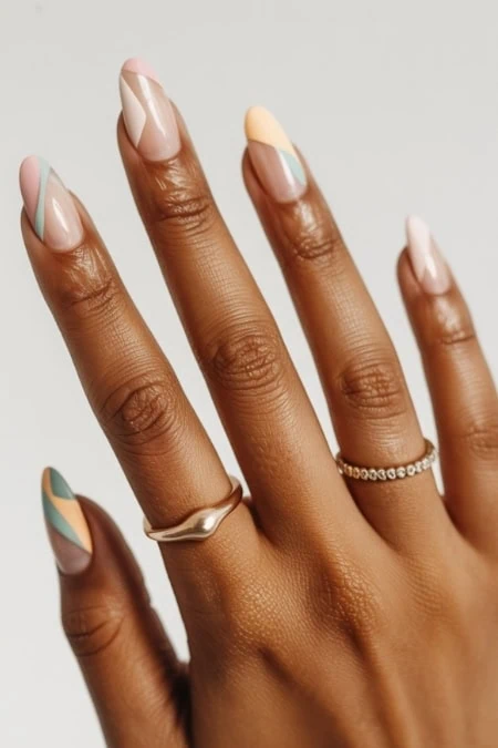 Colorful French manicured nails with pastel shades on a dark skin hand, featuring rings, elegant and trendy nail art, perfect for beauty and skincare inspiration, nail design ideas.