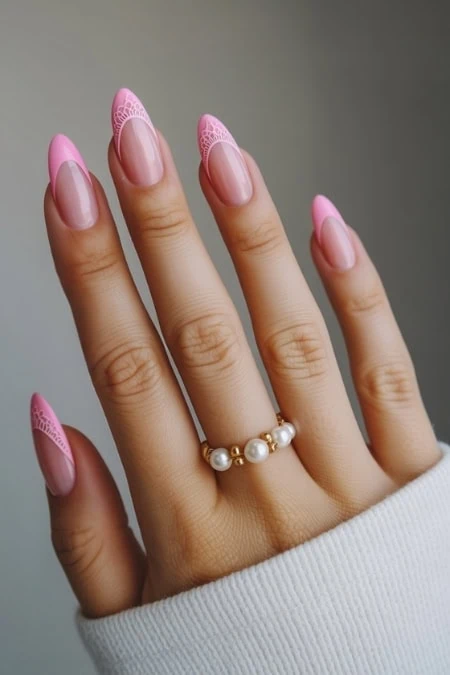 Elegant pink gel manicure with lace detail on long almond-shaped nails, showcasing trendy nail art and style.