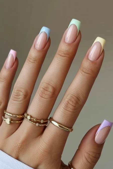 Colorful pastel French manicure with manicured nails and gold stacked rings, showcasing nail beauty, stylish accessories, perfect for spring or summer looks.