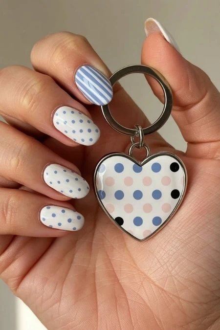 Polka dot nail art with blue, white, and pink design holding a heart-shaped keychain with matching polka dot pattern, perfect for trendy manicure and accessories.