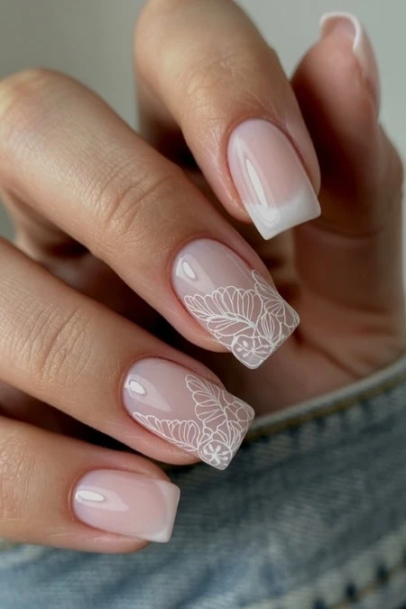 Elegant French manicure with intricate white floral nail art design, perfect for a chic and sophisticated look, ideal for beauty and nail art enthusiasts, by The Beauty Deep Life.