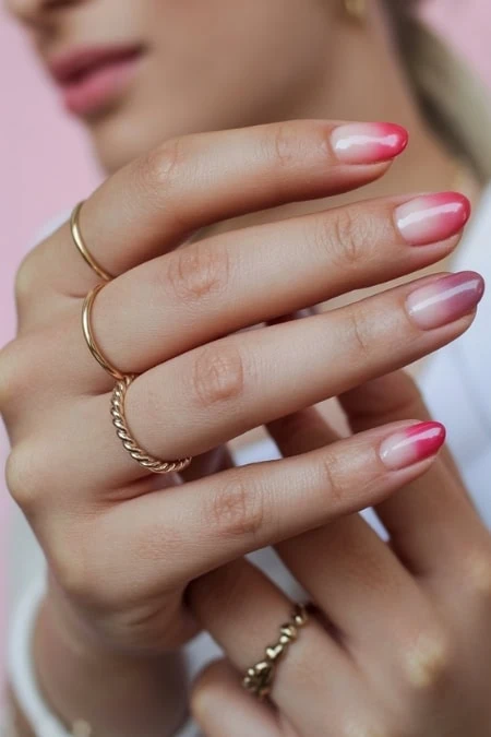 Delicate woman's hand with trendy pink ombré nails, gold rings, and elegant jewelry, showcasing modern beauty and manicure trends, perfect for beauty, fashion, and style content.