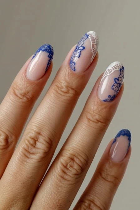 Delicate nude and blue floral lace nail art design on natural nails, featuring intricate detailing and elegant manicure for a sophisticated look. Perfect for special occasions or everyday fashion statements.