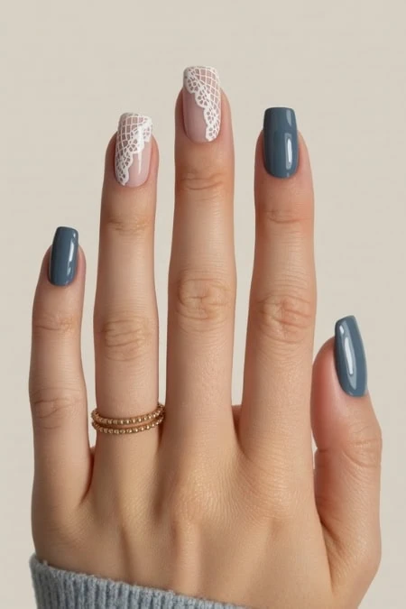 Elegant manicure with dark blue nails and intricate white lace nail art on the ring finger, showcasing stylish nail design, perfect for beauty, fashion, and nail art enthusiasts.