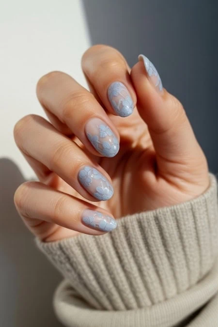 Beautiful manicured nails with light blue floral nail art on natural nails, manicured for an elegant look.