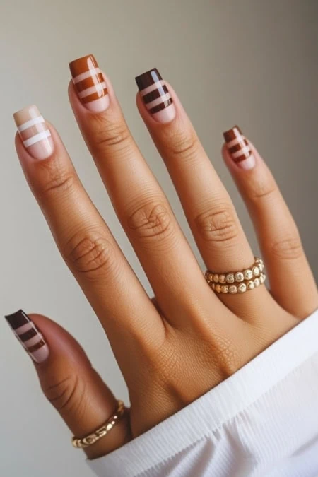 Vibrant multicolor striped nail art on well-manicured fingers featuring gold rings, ideal for fashion, beauty, and nail polish enthusiasts. Perfect for showcasing trendy nail designs.