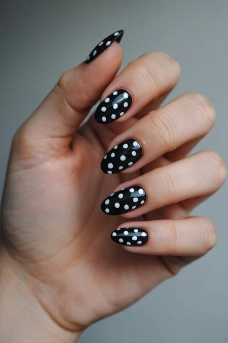Black and white polka dot nail design on manicured nails.
