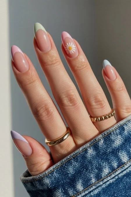 Colorful pastel nail art with floral design on index finger, featuring a natural background, showcasing trendy spring nail trends and manicure beauty tips.