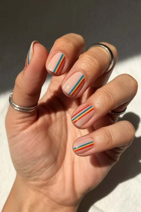 Colorful rainbow striped nail art on well-groomed nails, perfect for spring and summer beauty trends, featuring neutral base with vibrant rainbow accents, suitable for natural and artistic nail styles.