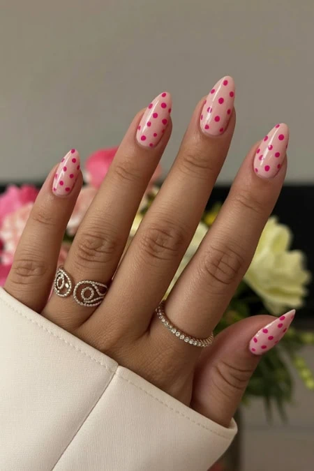 Polka dot nail art on manicured fingernails with elegant rings, showcasing beauty and nail design inspiration from The Beauty Deep Life.