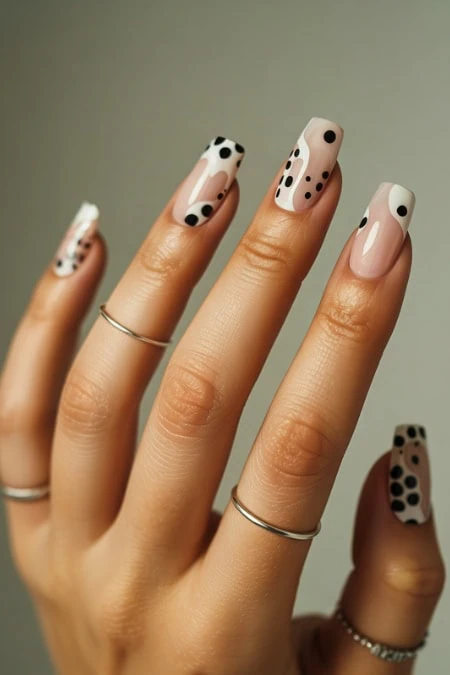 Elegant nail art with black and white polka dot design on long, almond-shaped nails, perfect for trendy beauty and manicure enthusiasts.