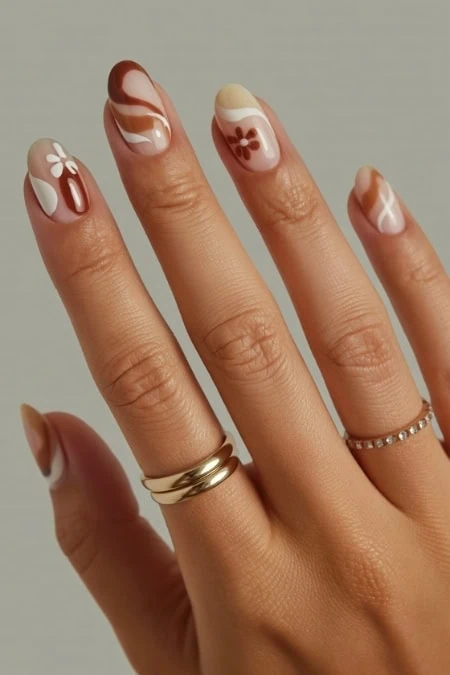 Delicate floral and swirl nail art with natural tones on manicured fingers, showcasing trendy summer nail designs and perfect for beauty and self-care enthusiasts.