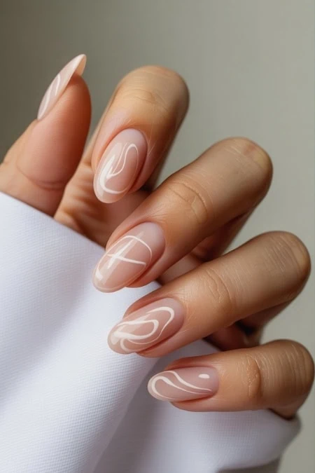 Elegant nude manicure with white abstract nail art design, showcasing stylish and modern nail art trends, perfect for beauty and self-care enthusiasts.