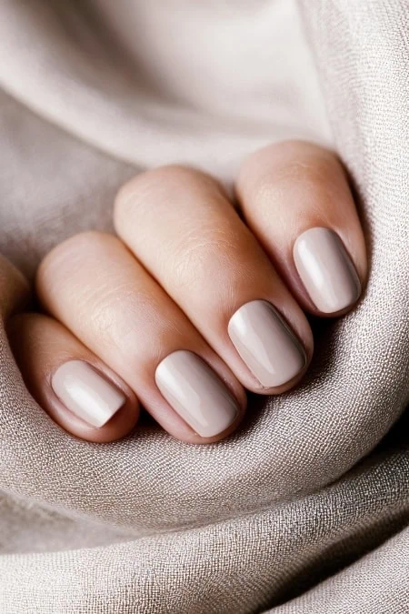 Soft beige manicure with polished nails on silky fabric, promoting nail care and beauty, perfect for skincare and beauty blog images.