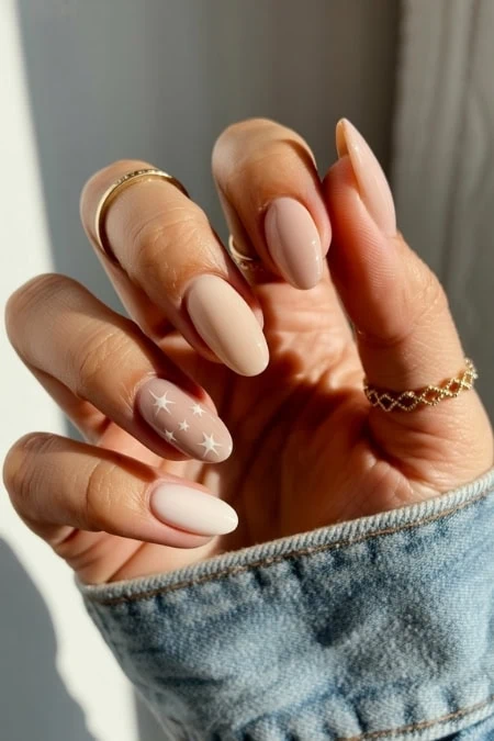 Elegant nude nail art with white star accents on well-groomed, glossy nails, showcasing trendy manicures for beauty and self-care. Perfect for stylish women interested in nail design and beauty trends.