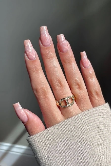 Dainty gold ring with embedded gemstones on a woman's finger, manicured nails, close-up of elegant jewelry and stylish nail art, ideal for beauty and fashion enthusiasts.