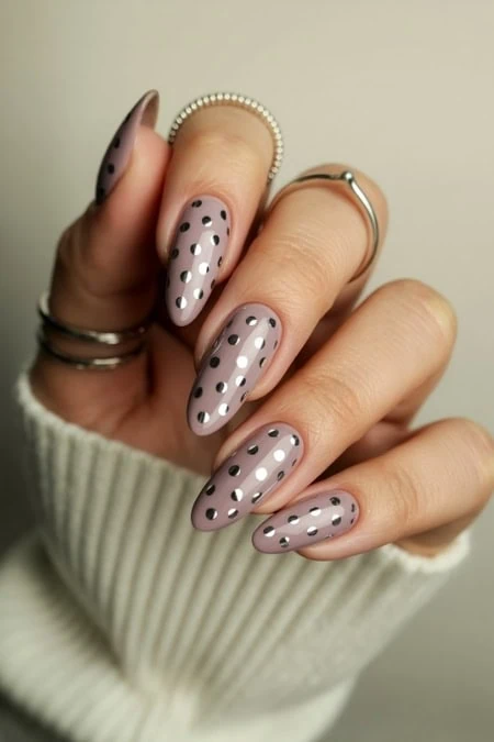 Polka dot almond-shaped nude nail art with silver accents, perfect for elegant, trendy manicure looks.