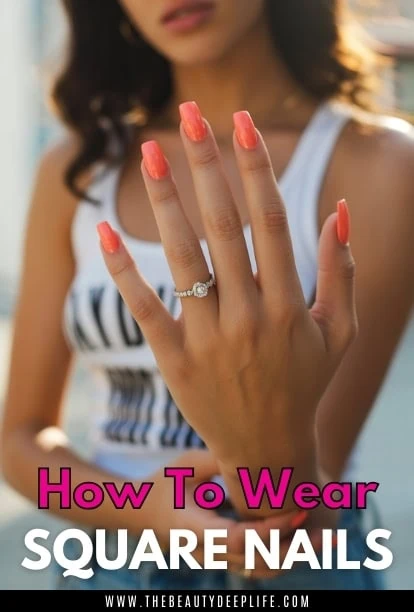woman's hand showcasing perfectly manicured square nails with coral nail polish, emphasizing nail beauty and grooming.