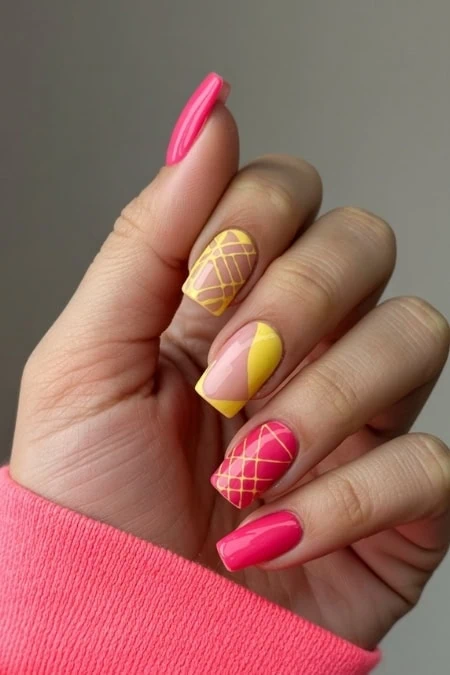 Bright pink and yellow nail art featuring geometric patterns and a glossy finish, perfect for summer fashion and beauty.