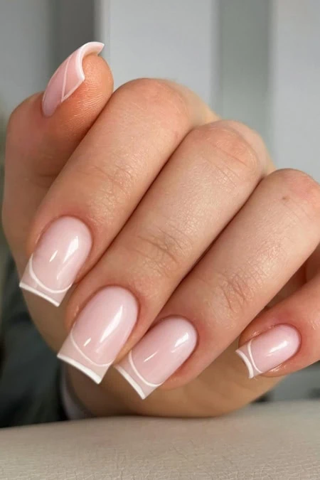 Elegant French manicure with natural pink base and white tips on well-groomed nails, emphasizing beauty, self-care, and professional nail art for a polished look.