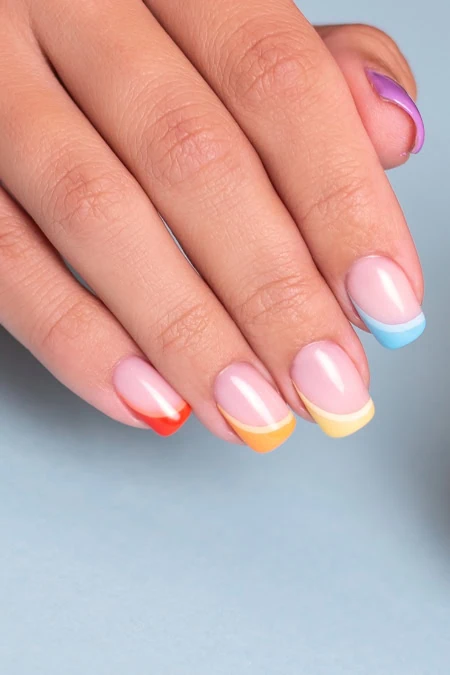 Colorful rainbow French tips on well-groomed nails.