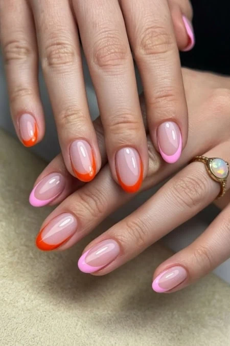 Beautifully manicured hands with pink and orange French tips, highlighting modern nail art design perfect for beauty enthusiasts and professional salons.
